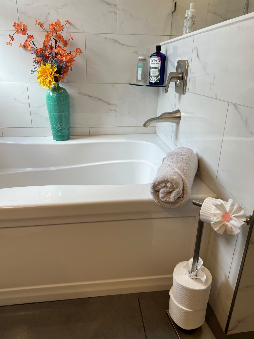 Bathtub with rolled towel and fresh flowers