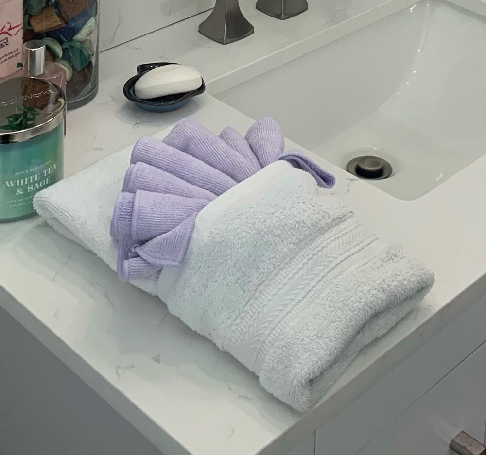 Hand towel folded with a lilac washcloth on the vanity